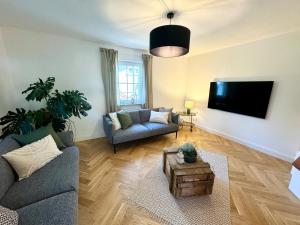 ein Wohnzimmer mit Couch und Fernseher in der Unterkunft Stilvolles Haus mit Naturgarten & Weitblick - für Familien & Freunde in Oberschwarzach