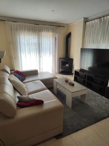 a living room with a couch and a flat screen tv at Chalet en la almadrava in Denia