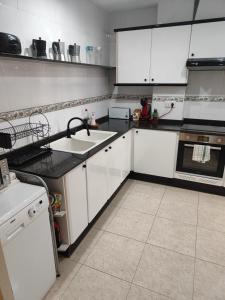 a kitchen with white cabinets and a sink at Chalet en la almadrava in Denia +16 photos