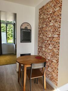 a dining room with a wooden table and a brick wall at La Grelauderie 7 in Saintes