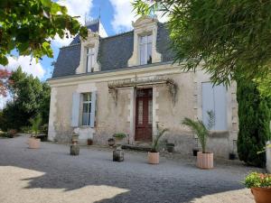 a white house with a red door and potted plants at La Grelauderie 7 in Saintes