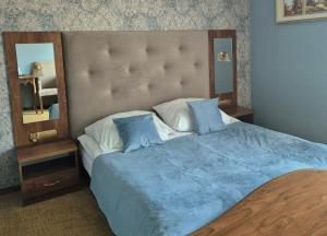 a bedroom with a large bed with a large headboard at Dworek Nad Stawem & Łaźnia Piwna in Ostrów Mazowiecka