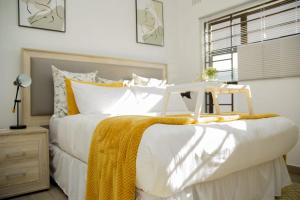 a bedroom with a bed with white sheets and yellow blankets at Sunset Bliss Paradise in Lilongwe in Lilongwe