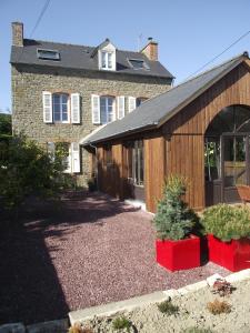 une grange avec deux plantes en pot devant une maison dans l'établissement Chambres d'hôtes Le Clos d'Enhaut, à Dinard