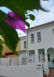 a white house with a white fence and a purple flower at La casa del Genil in Granada +28 photos