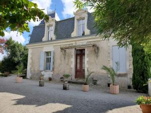 a white house with a red door and potted plants at La Grelauderie 8 in Saintes
