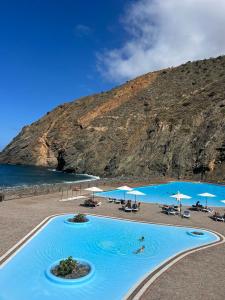 a large swimming pool on a beach with a mountain at Tamahuche Hotel Rural in Vallehermoso