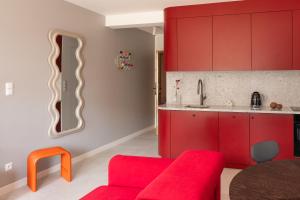 a kitchen with red cabinets and a red couch at Apartament KOPENHAGA - nowoczesny i stylowy apartament w centrum miasta z miejscem parkingowym in Nowy Targ