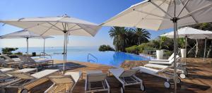 a group of chairs and umbrellas next to a pool at Exclusiva villa con piscina climatizada Colinas in Orihuela