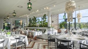 a restaurant with white tables and chairs and large windows at Exclusiva villa con piscina climatizada Colinas in Orihuela