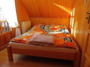 a bed in a cabin with an orange comforter at Domki ogrzewane Sokół in Władysławowo