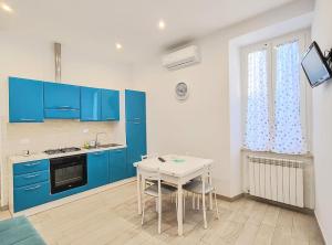 a kitchen with blue cabinets and a white table at La Vie est Belle in Nettuno