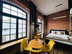 a bedroom with a bed and a wooden table and chairs at Tkalnia Snu in Łódź
