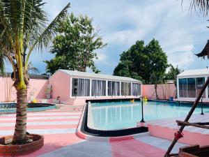 ein Swimmingpool mit einer Palme neben einem rosa Gebäude in der Unterkunft Lamoon Villa in Hat Yai