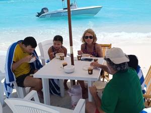 a group of people sitting at a table on the beach at Kokaa Villaa Maaenboodhoo - The speedboat from Malé to the hotel departs at 1130 every Monday Thursday and Saturday and from the hotel to Malé at 0630 and five domestic flights are available every day in Dhaalu Atoll