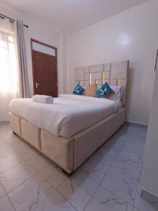 a large bed with blue pillows in a bedroom at Ravic Homes Studio in Nairobi