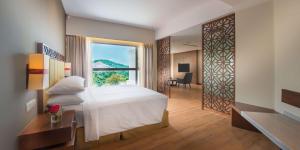 a hotel room with a bed and a large window at DoubleTree Resort by Hilton Hotel Penang in Batu Ferringhi