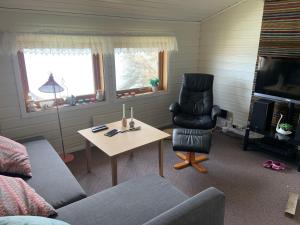 a living room with a couch and a table and a chair at Villa med sauna ute, egen båt, naust og kai in Breidvik
