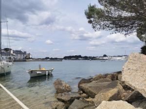 a small boat in the water next to some rocks at La maison Kerserho in Plouhinec