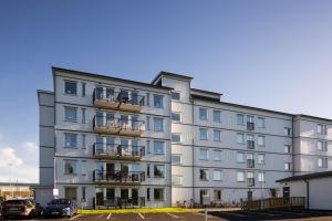 a large building with cars parked in a parking lot at Guestly Homes - 1BR Corporate Comfort in Boden