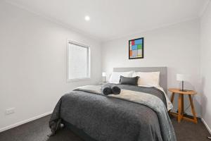 a white bedroom with a bed and a table at Frankton Townhouse Retreat - Central in Hamilton