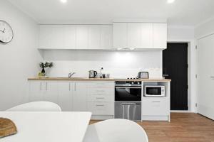 a kitchen with white cabinets and a clock on the wall at Frankton Townhouse Retreat - Central in Hamilton