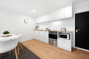 a kitchen with white cabinets and a black door at Frankton Townhouse Retreat - Central in Hamilton +9 photos