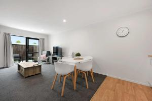a living room with a table and a clock on the wall at Frankton Townhouse Retreat - Central in Hamilton