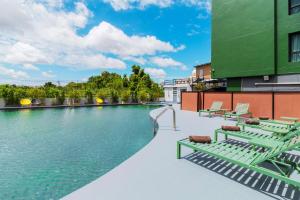 a swimming pool with chaise lounge chairs next to a building at SureStay By Best Western Iconic Suvarnabhumi in Samut Prakan