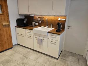 a kitchen with white cabinets and a sink at Grüne Stadtrandidylle - 22 min bis Potsdamer Platz in Berlin