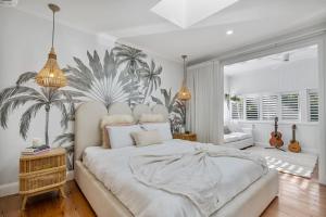 - une chambre avec un grand lit blanc orné d'une fresque murale de palmiers dans l'établissement La Petite Boheme-Pet friendly - boat parking, à Cannonvale
