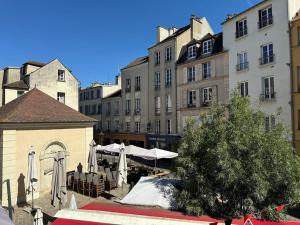 a group of buildings with tables and umbrellas at Hyper centre st Germain en laye appt de standing in Saint-Germain-en-Laye