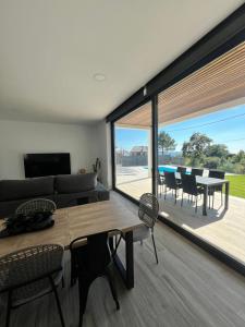 a living room with a table and chairs and a large window at Casa OS BALCÓNS in Boiro
