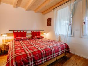 a bedroom with a red bed and a window at Apartment Family House by Interhome in Moena