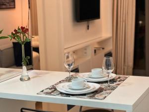 a table with two glasses and plates and coffee cups at Habitarte Brooklin in Sao Paulo