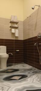 a bathroom with a sink and a toilet and towels at SAROJINI GARDEN HOTEL & RESTAURANT in Begusarai