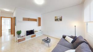 Una sala de estar con un sofá y un televisor. en Holidoo Casa Marbella, en Los Alcázares