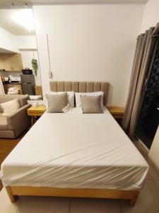 a large white bed in a room with a couch at Jinh's place to STAYCATION in Manila