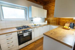 a kitchen with white cabinets and a stove and a window at Cosy countryside cottage with indoor fireplace in Sodražica