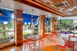 a restaurant with tables and chairs and large windows at Cleo Balaikota Surabaya in Surabaya