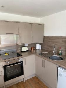 a kitchen with white cabinets and a sink at Flat 1, Coneygre Farm in Hoveringham
