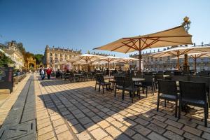 an outdoor patio with tables and chairs and umbrellas at Le Grand Amerval - Joli appartement climatisé in Nancy