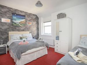 a bedroom with two beds and a brick wall at Wave from it All in Llandudno