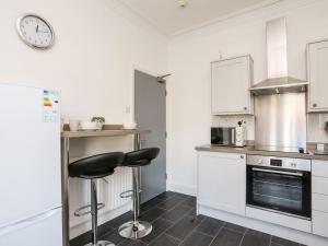 a kitchen with a black stool in a white kitchen at Wave from it All in Llandudno +2 photos