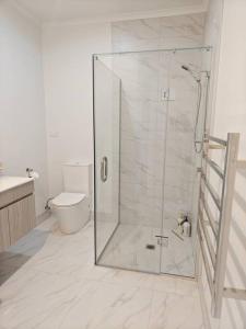 a bathroom with a glass shower with a toilet at Contemporary New 2-Bedroom Home in Hamilton