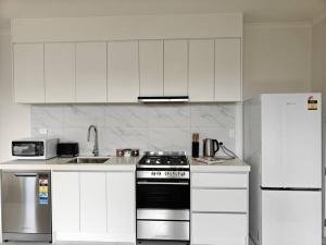 a white kitchen with a stove and a refrigerator at Contemporary New 2-Bedroom Home in Hamilton +9 photos