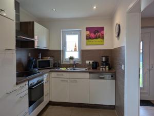 a kitchen with white cabinets and a sink at Ferienhaus Ostara in Hasselfelde