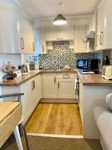 a kitchen with white cabinets and a wooden floor at Seaforth Cottage -Dog friendly, Historical Fishertown, central location in Nairn +13 photos