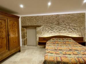 ein Schlafzimmer mit einem Bett und einer Steinwand in der Unterkunft L'Oxalis doré in Frontenas