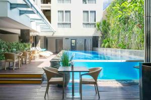 a patio with a table and chairs next to a swimming pool at Solaris Hotel Kuta in Kuta